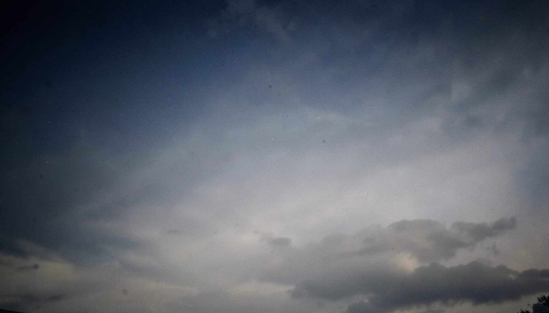 Soft gradient of deep navy and steel grey sky above a muted cloud layer, calm and atmospheric