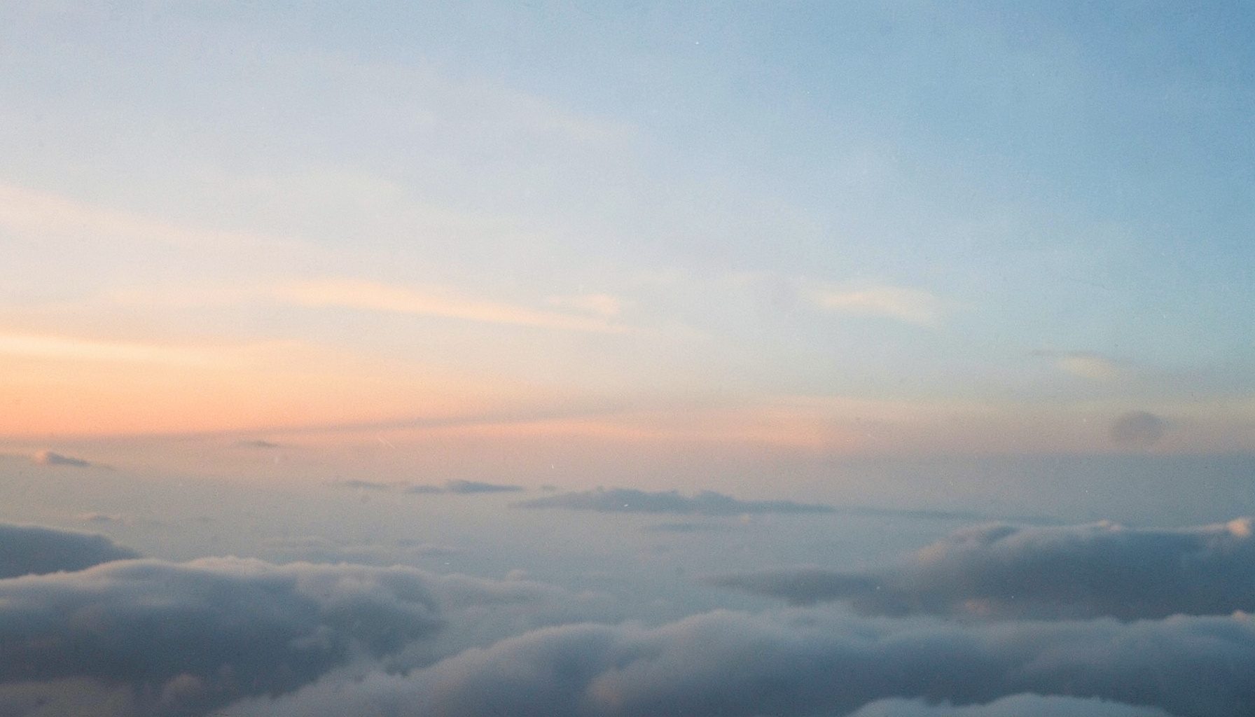 Wide dawn sky with soft orange and blue gradient above a calm cloud layer, atmospheric and anonymous