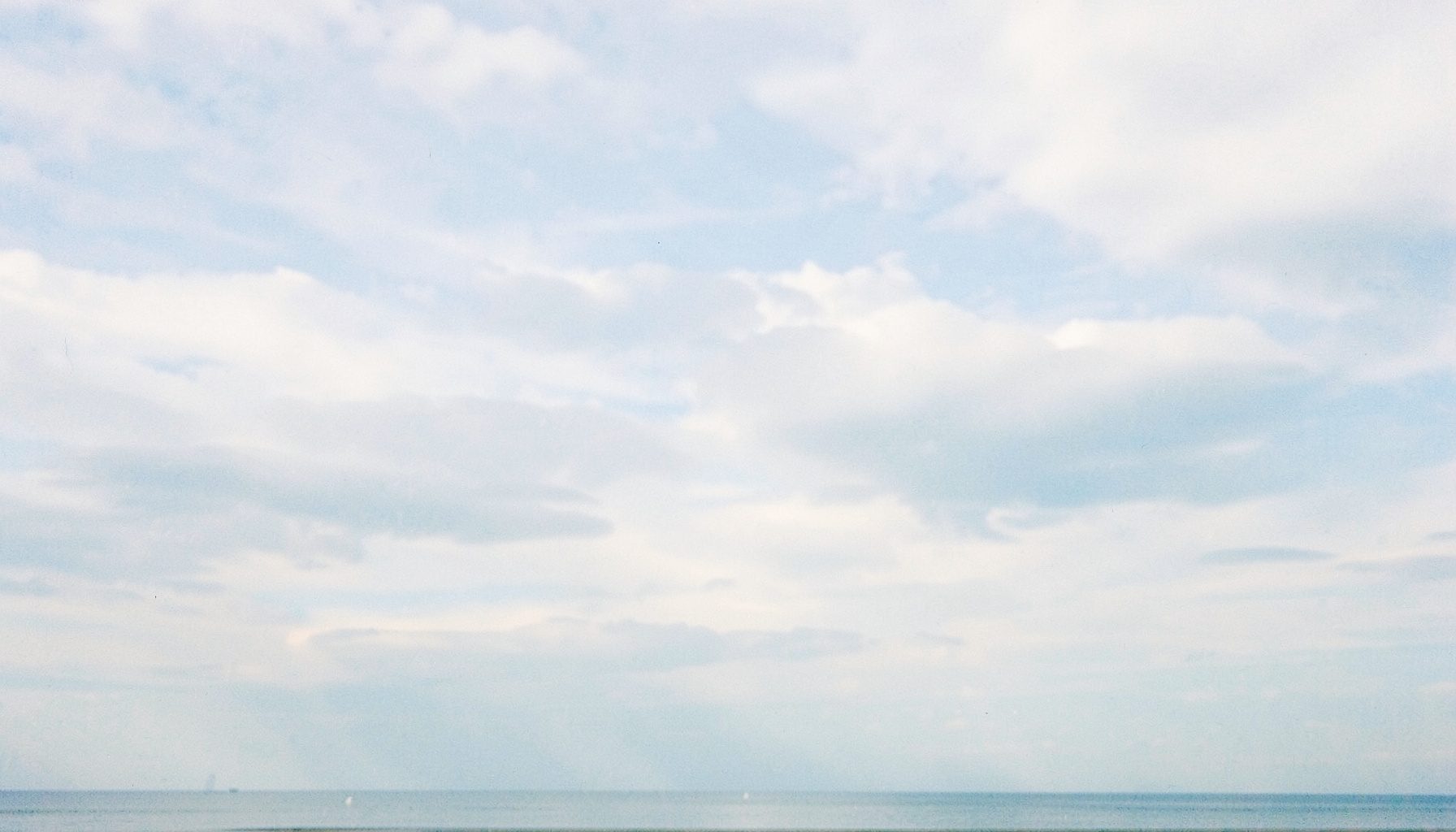 Soft cloudy sky in pale blue and white over a calm horizon, evoking the calm before takeoff